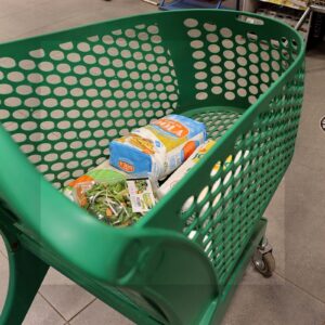 Carro de supermercado en un pasillo de alimentación como imagen editorial sobre precio de la cesta de la compra