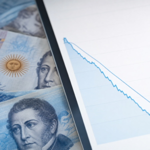 Billetes argentinos junto a un gráfico financiero descendente que representa la desinflación