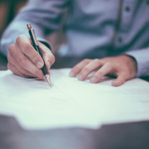 Primer plano de una persona firmando documentos sobre una mesa